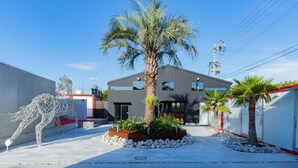 A modern building with a central palm tree, surrounded by a landscaped area with rocks and plants. - awaJ Beach Club (Awaji)