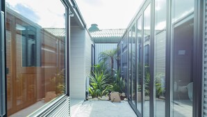 A modern building with large glass windows and doors, a tiled floor, and a small garden area with plants and rocks. - awaJ Beach Club (Awaji)