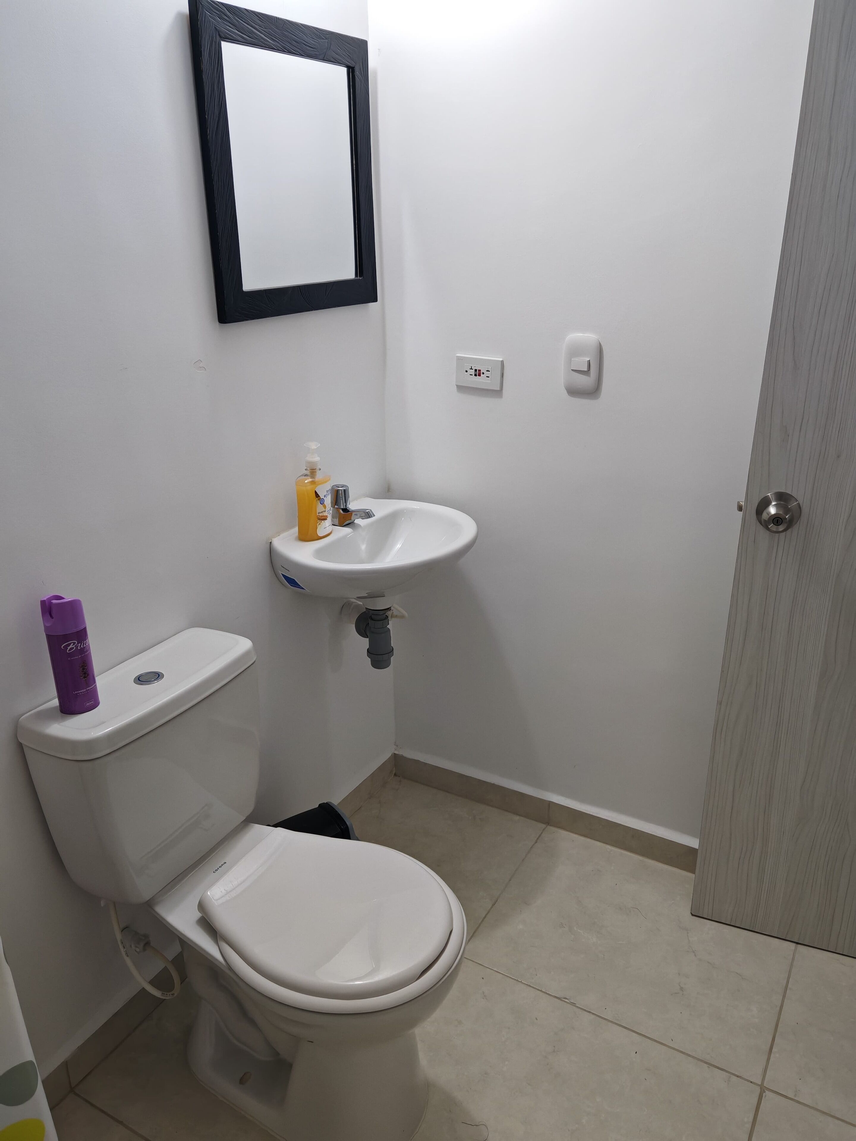 Ein kleines, sauberes Badezimmer mit Toilette, Waschbecken und Spiegel.