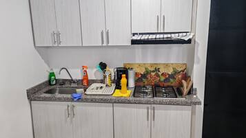 A kitchen with white cabinets, a granite countertop, a coffee maker, a gas stove, and various kitchen items.