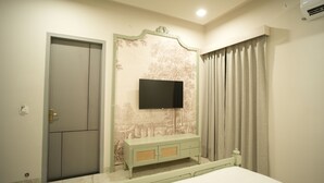 A bedroom with a bed, a TV mounted on a decorative wall, a wardrobe, and a curtain. - Angelo's farm (Amer)