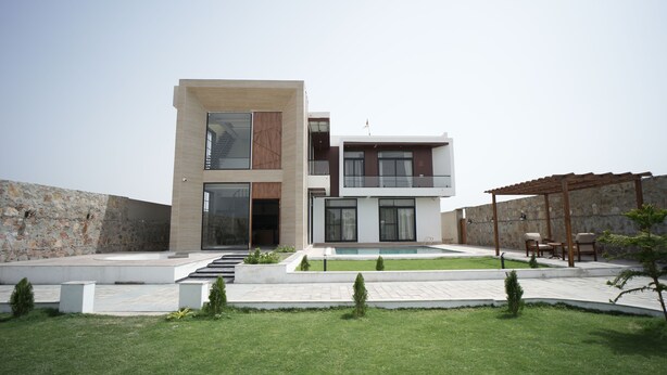 A modern two-story house with a swimming pool, a covered patio, and a stone wall. - Angelo's farm (Amer)