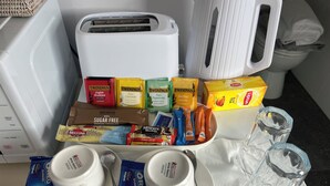 Un plateau de petit-déjeuner contenant divers aliments, un grille-pain, une machine à café et deux tasses.