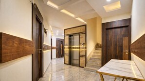 A modern hallway with marble flooring, wooden doors, and a marble table with a gold frame. - Diamond palace (bengalore)