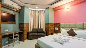A hotel room with a bed, a desk, a chair, a television, and a window with curtains. - Diamond palace (bengalore)