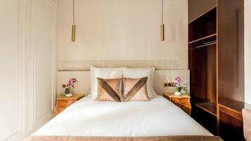 A neatly arranged bedroom with a large bed, two bedside tables, a wardrobe, and pendant lights.