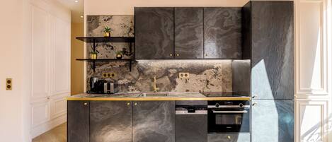 A modern kitchen with dark cabinetry, a marble backsplash, and built-in appliances.