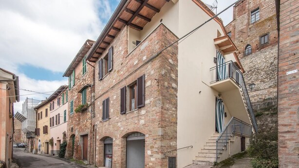A narrow street lined with traditional brick buildings, featuring balconies and arched doorways.