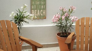 Two wooden chairs with potted plants, a wall with a sign, and a textured wall.
