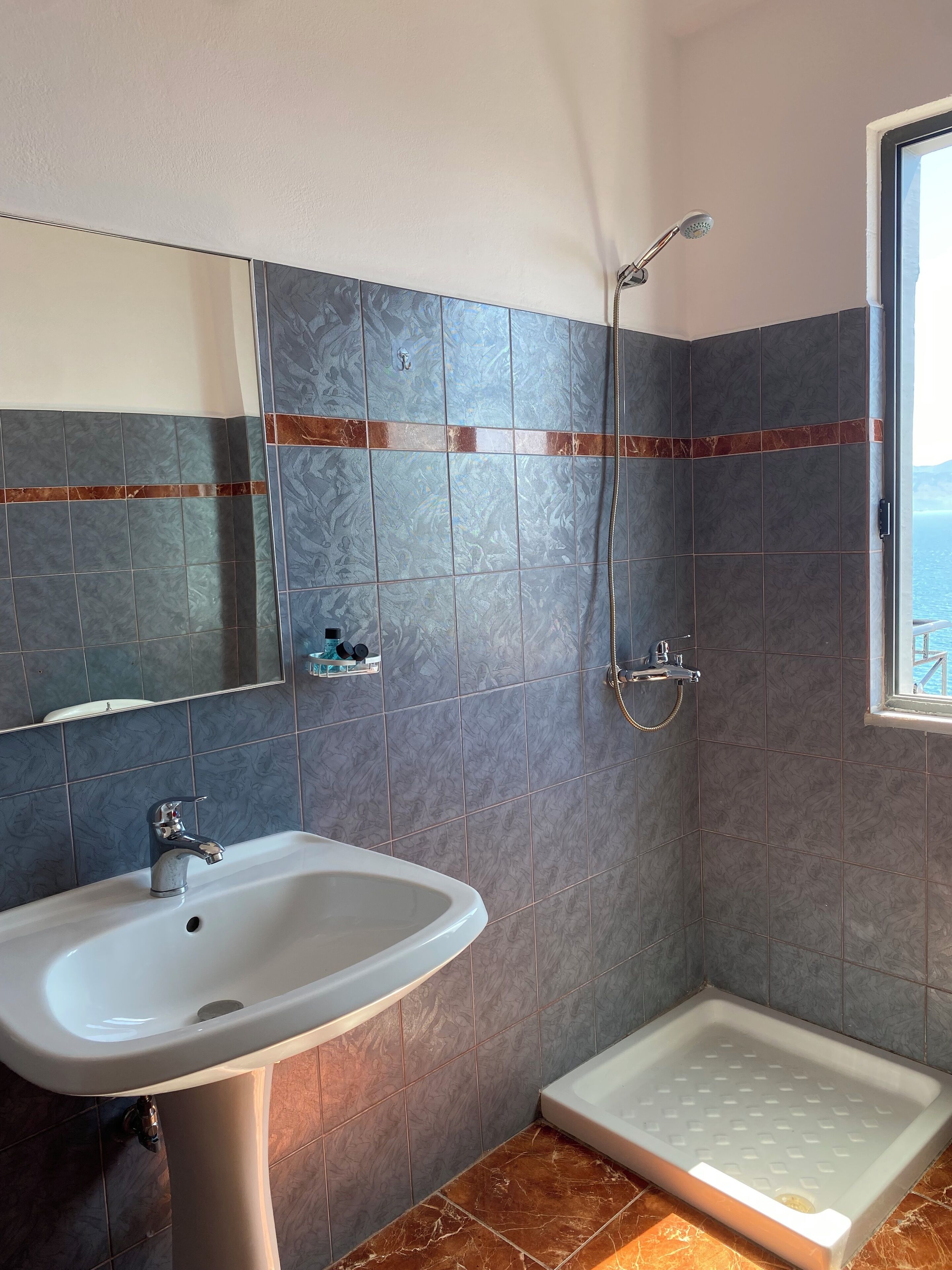 A bathroom with a sink, shower, and a window with a view.