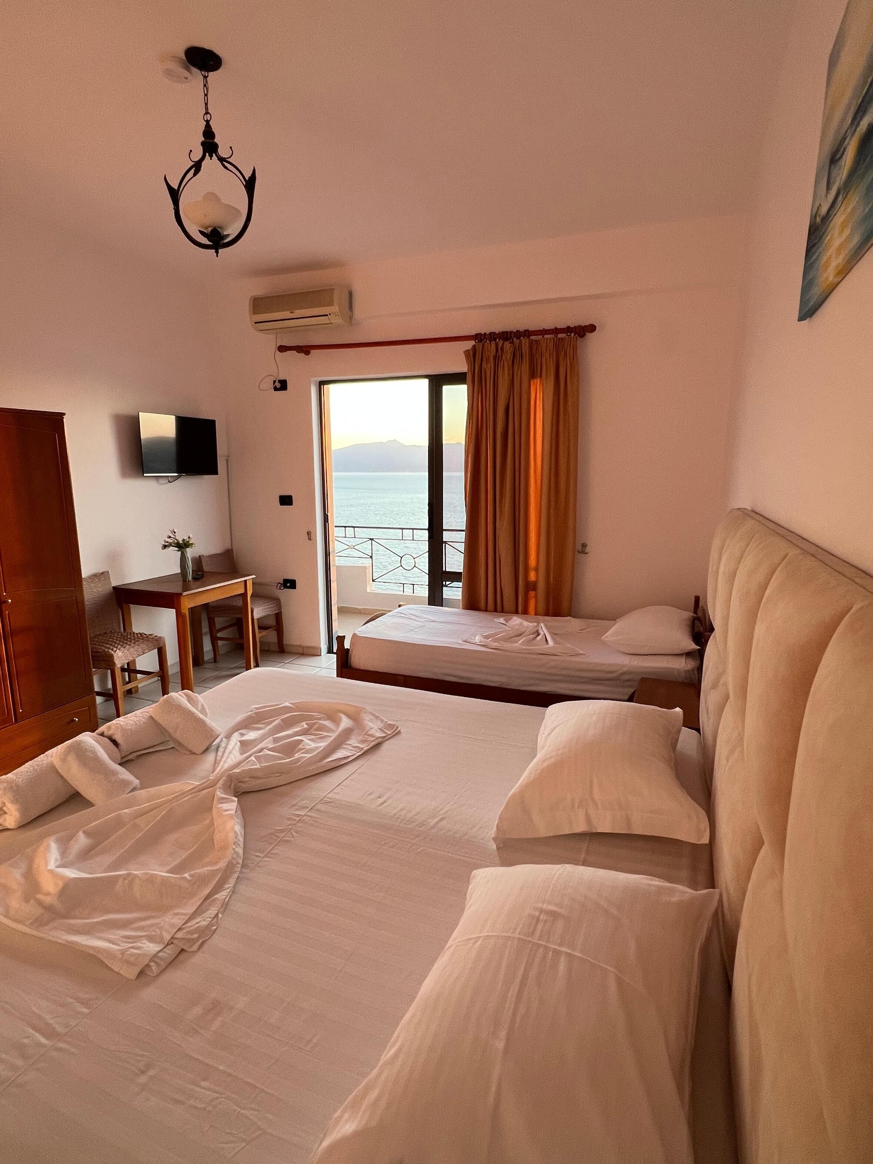 Habitación de hotel con dos camas, un escritorio, una silla y un televisor.