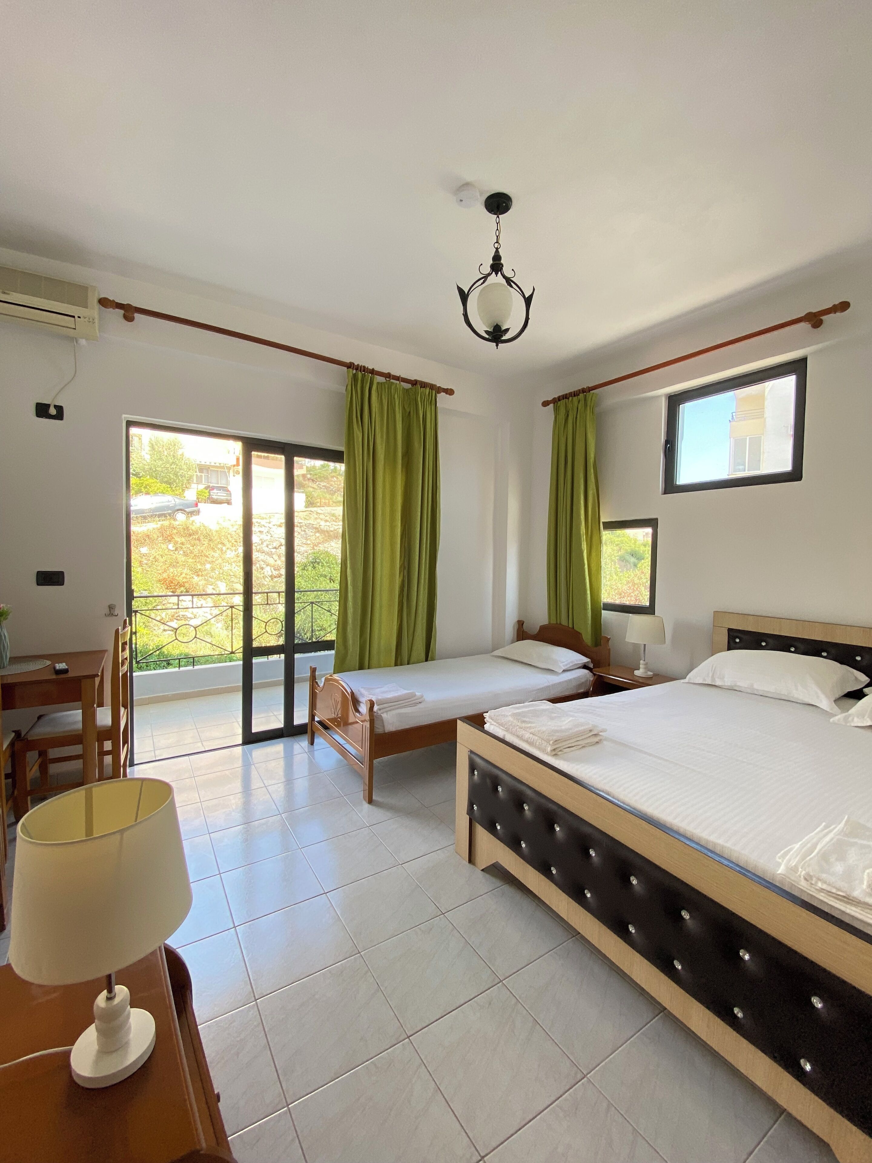 Habitación de hotel con cama, escritorio, silla, lámpara y vistas al exterior.