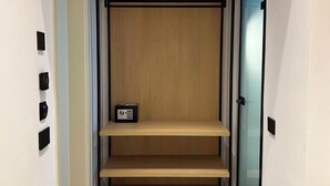 Un couloir étroit doté d’un plancher en bois, d’une bibliothèque intégrée et d’une porte avec un panneau en verre dépoli.