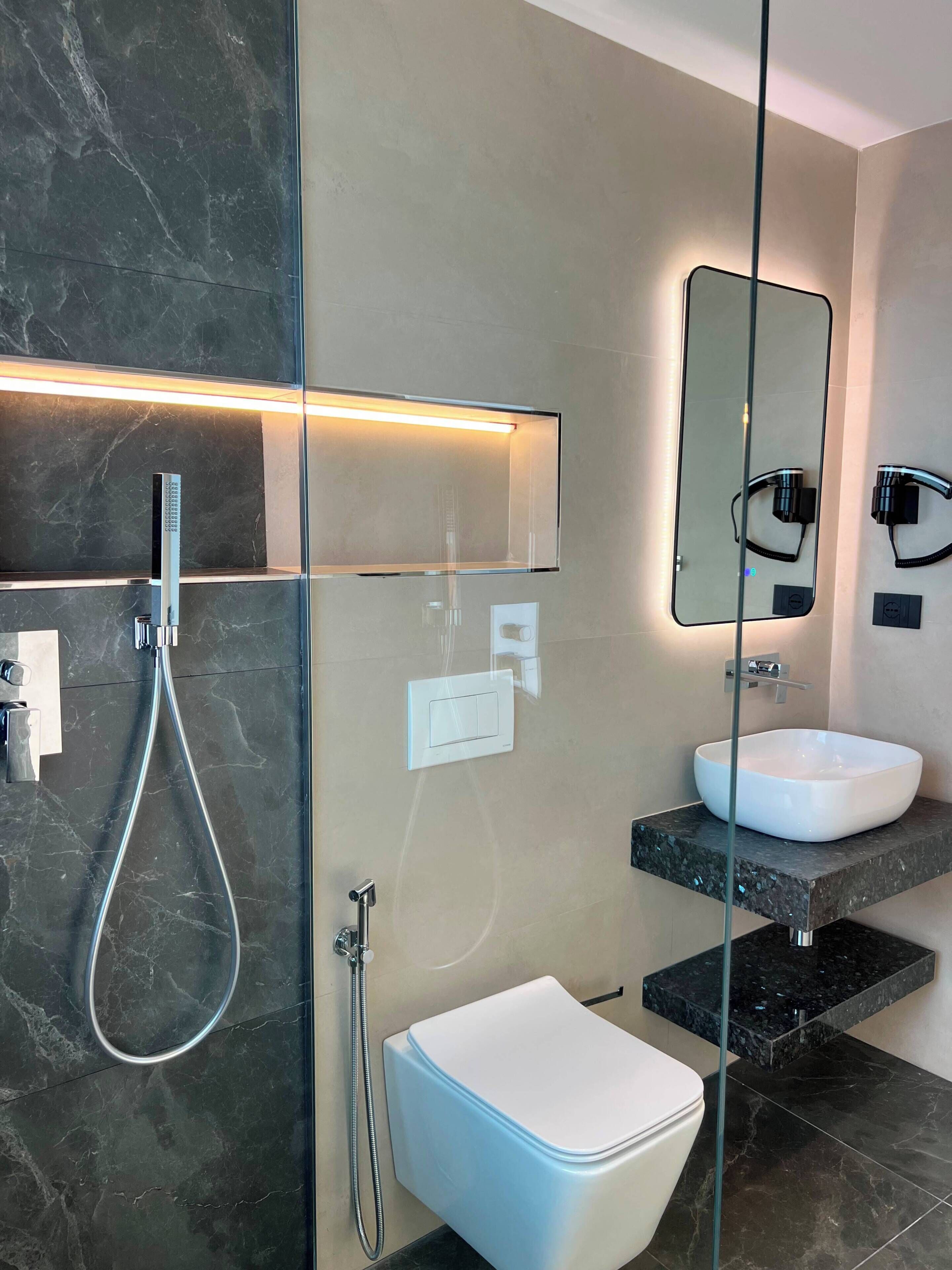 A modern bathroom with a glass-enclosed shower, a white toilet, and a vanity with a sink.
