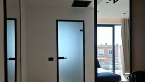 A hotel room with a bed, a desk, and a view of the outside. - Blue Waves Hotel & Suites (Sarandë)