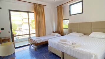 Habitación de hotel con dos camas, un balcón, ventilador de techo y vistas al exterior.
