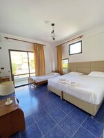 Habitación de hotel con dos camas, un balcón, ventilador de techo y vistas al exterior.