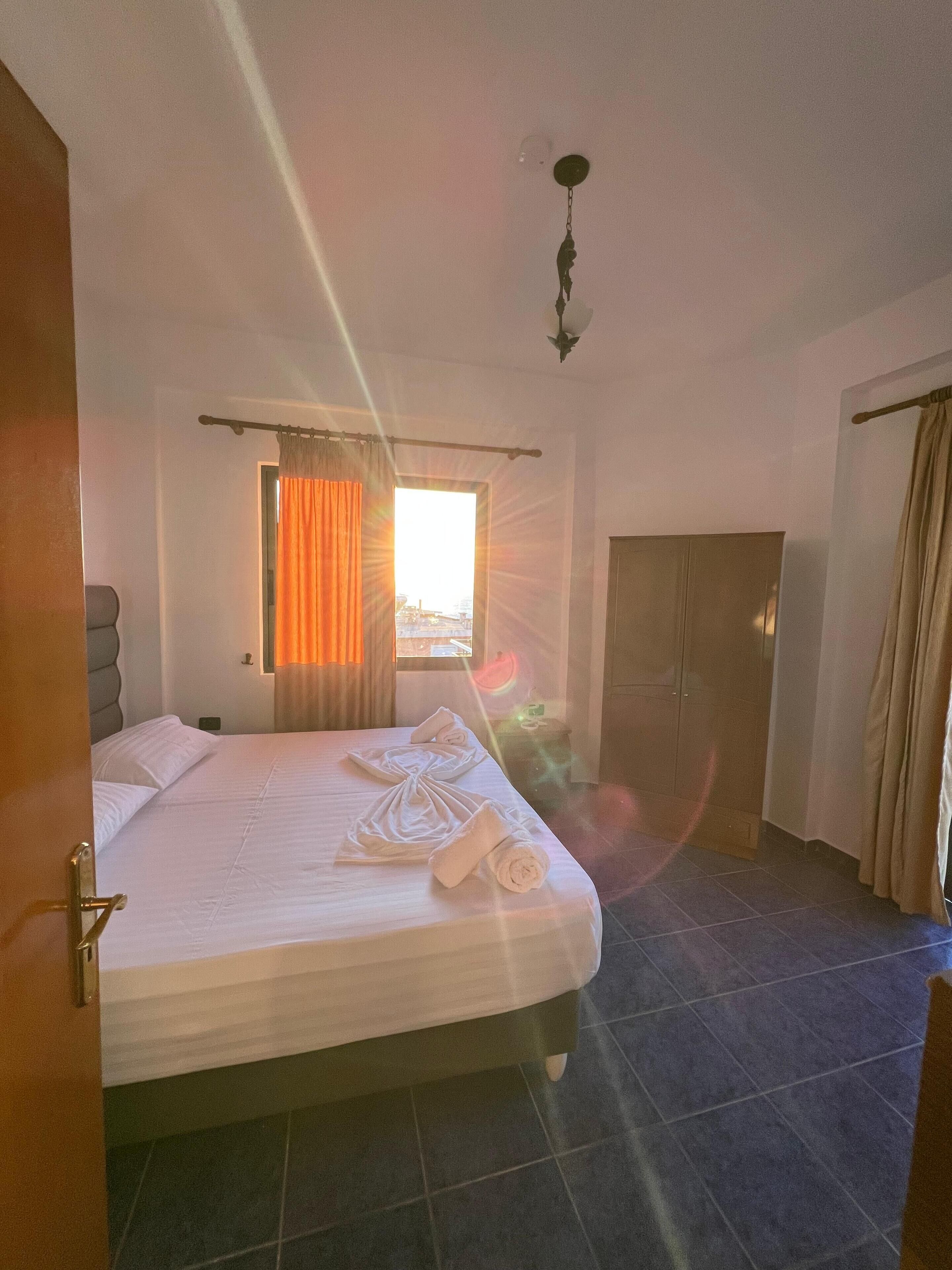 Une chambre d’hôtel avec un lit, une armoire, une salle de bain et une fenêtre avec des rideaux.
