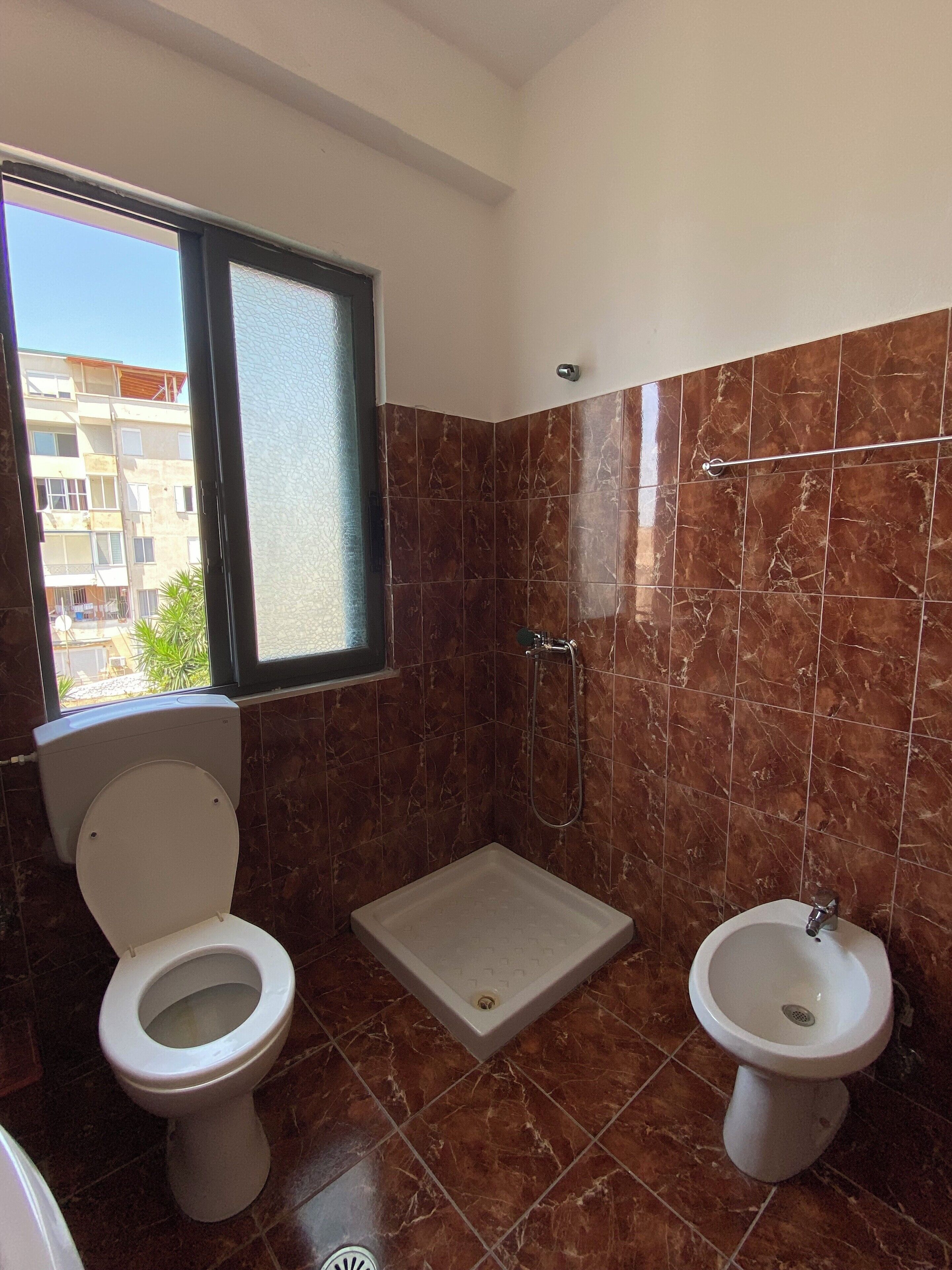 A bathroom with a toilet, bidet, and shower.