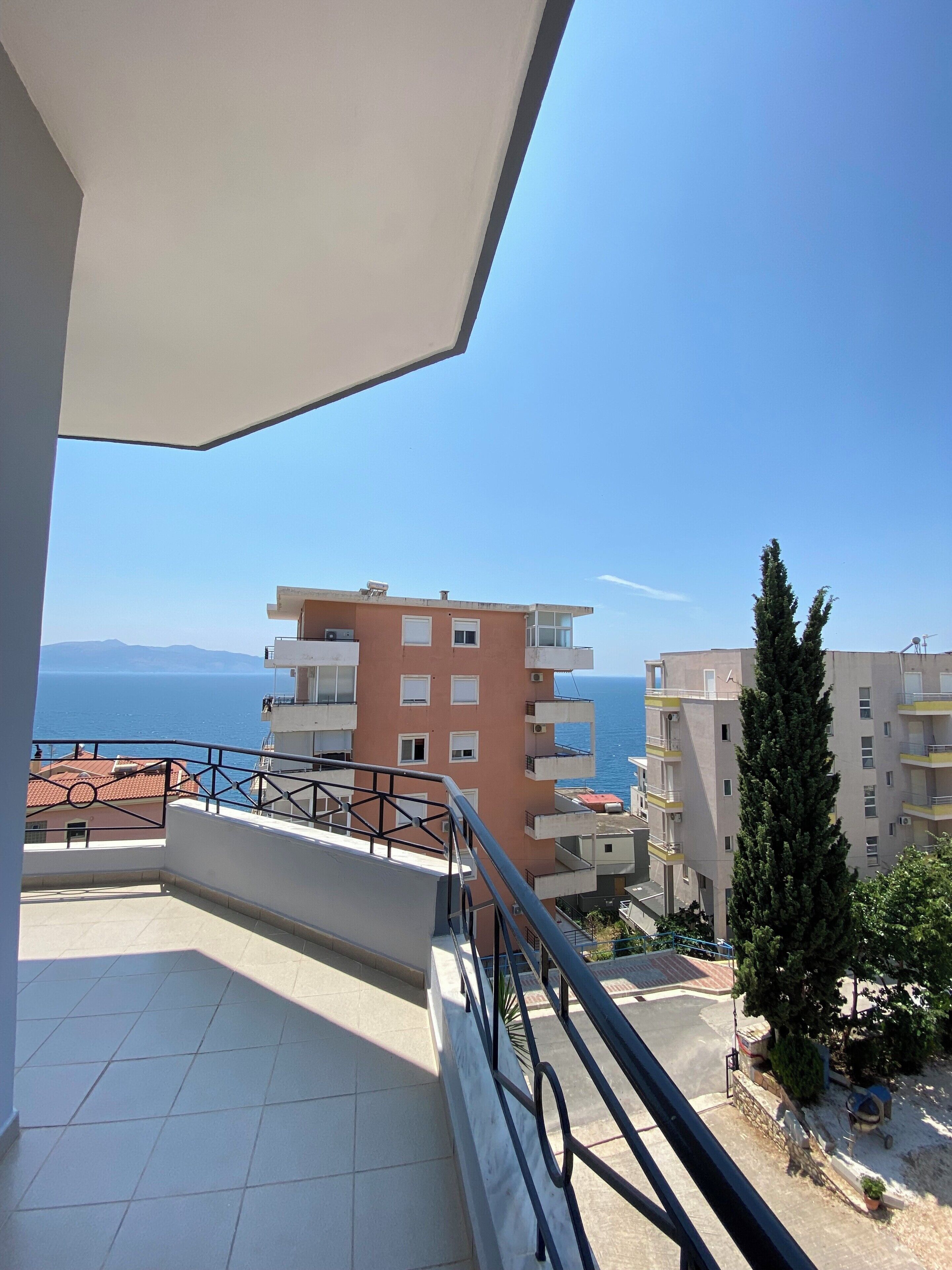 A balcony with a view of the sea and buildings.