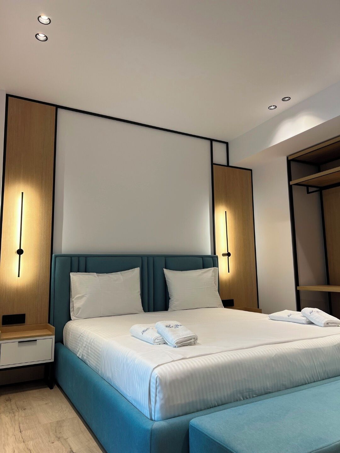 A modern hotel room with a large bed, bedside tables, and a wardrobe.