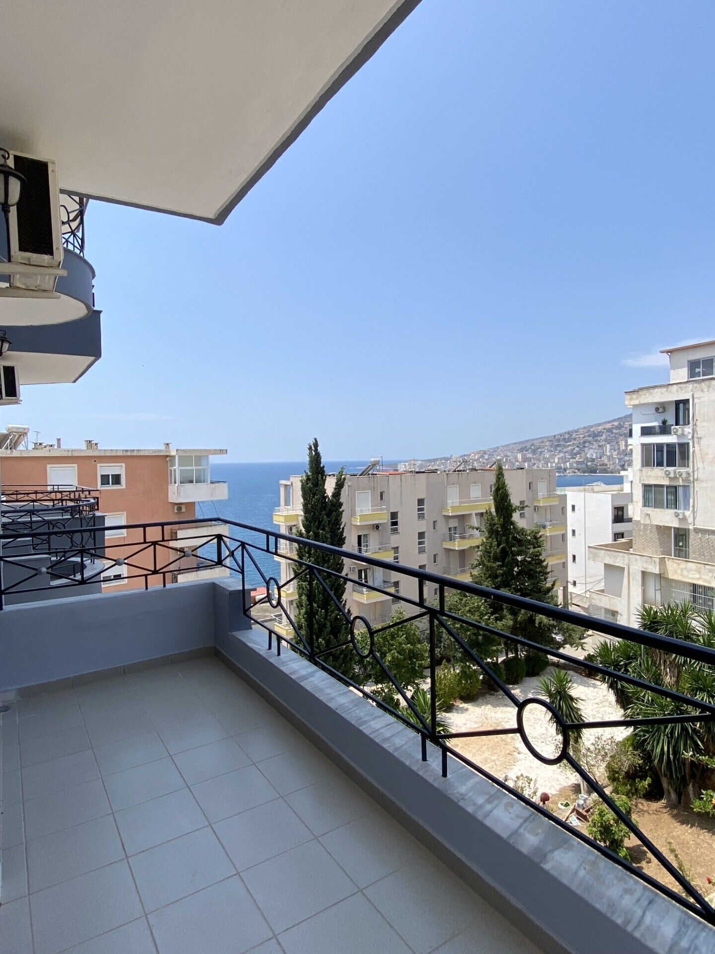 A balcony with a clear view of the sea and cityscape.