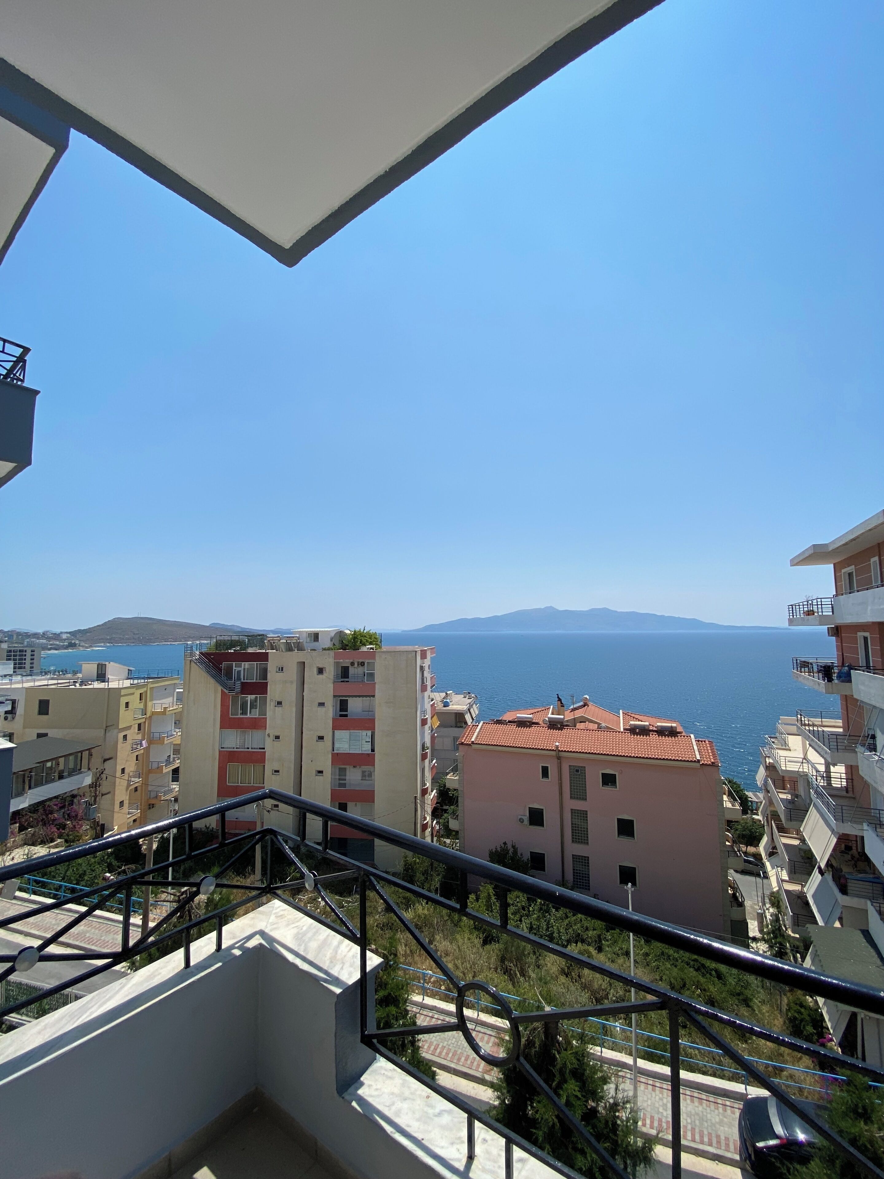 A balcony with a view of the sea and buildings.