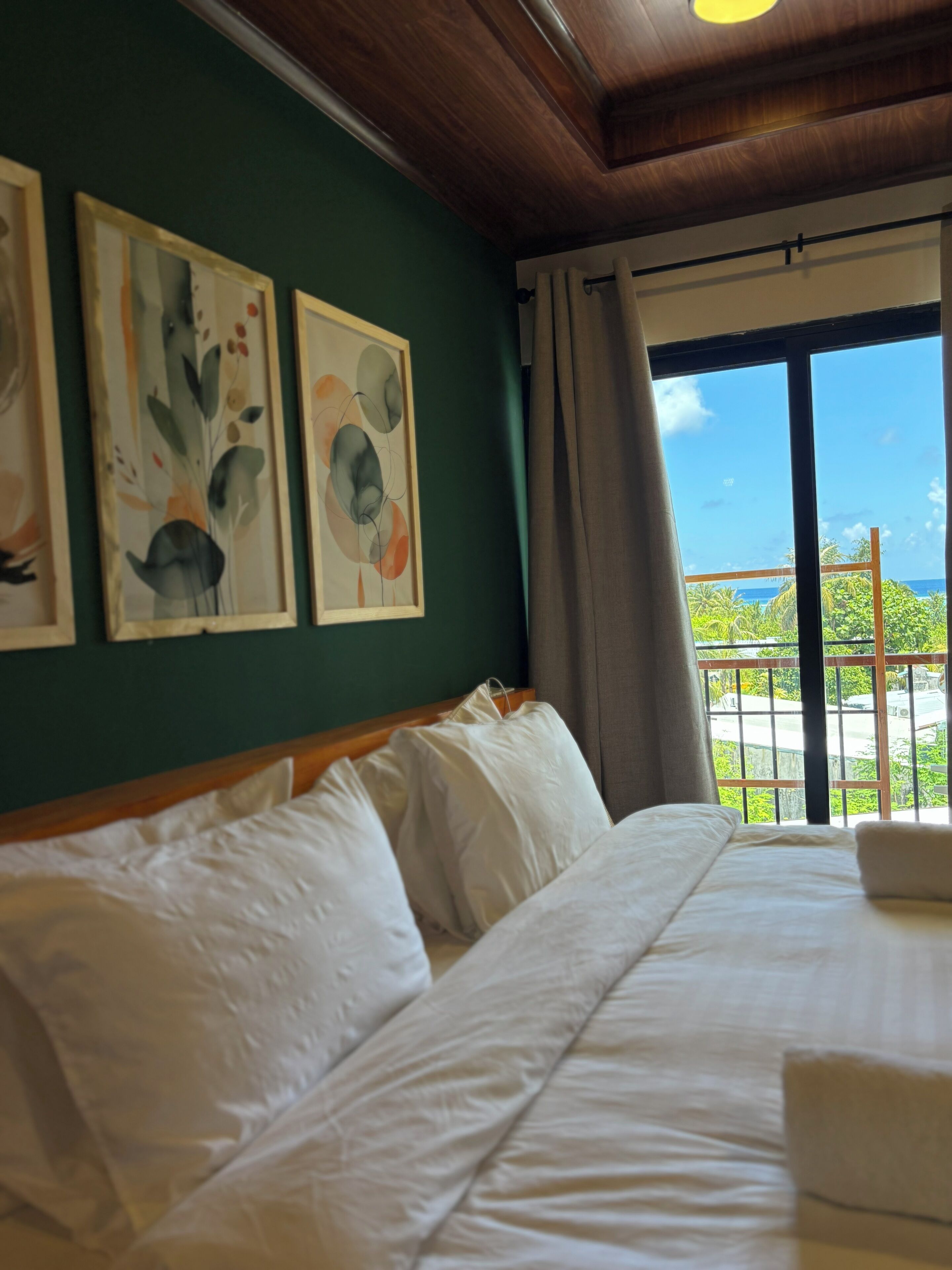 A hotel room with a bed, artwork on the wall, and a view of the ocean.