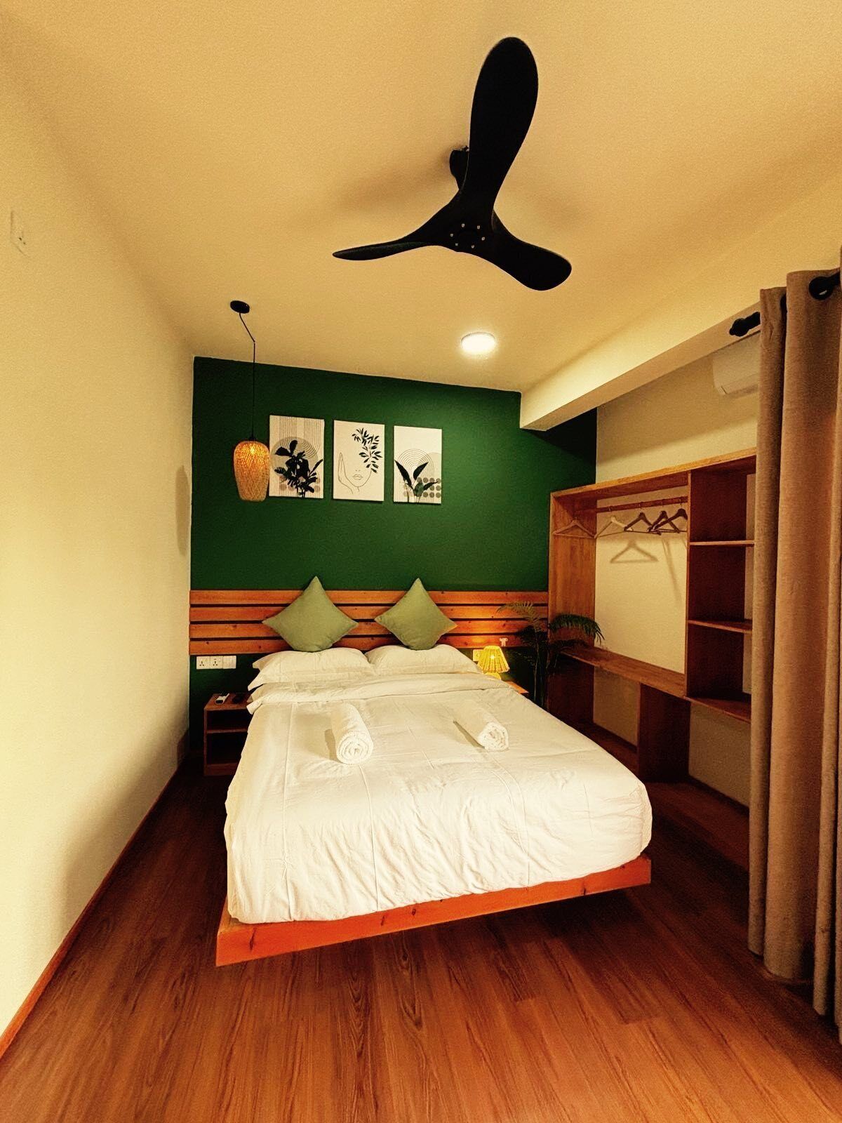 A neatly arranged bedroom with a bed, bedside tables, a hanging light fixture, and a ceiling fan.
