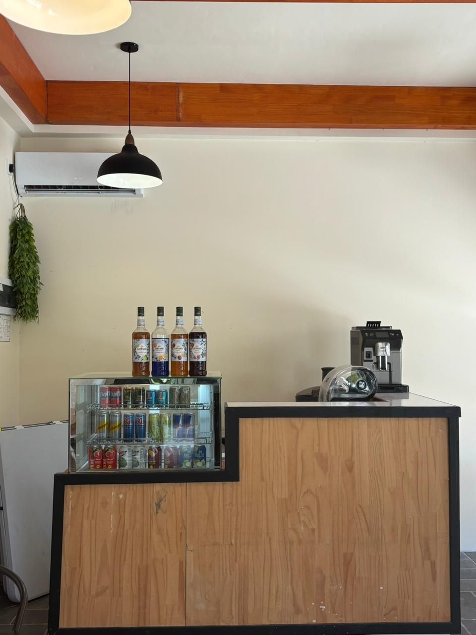 A reception area with a wooden counter, a coffee machine, and a beverage cooler.