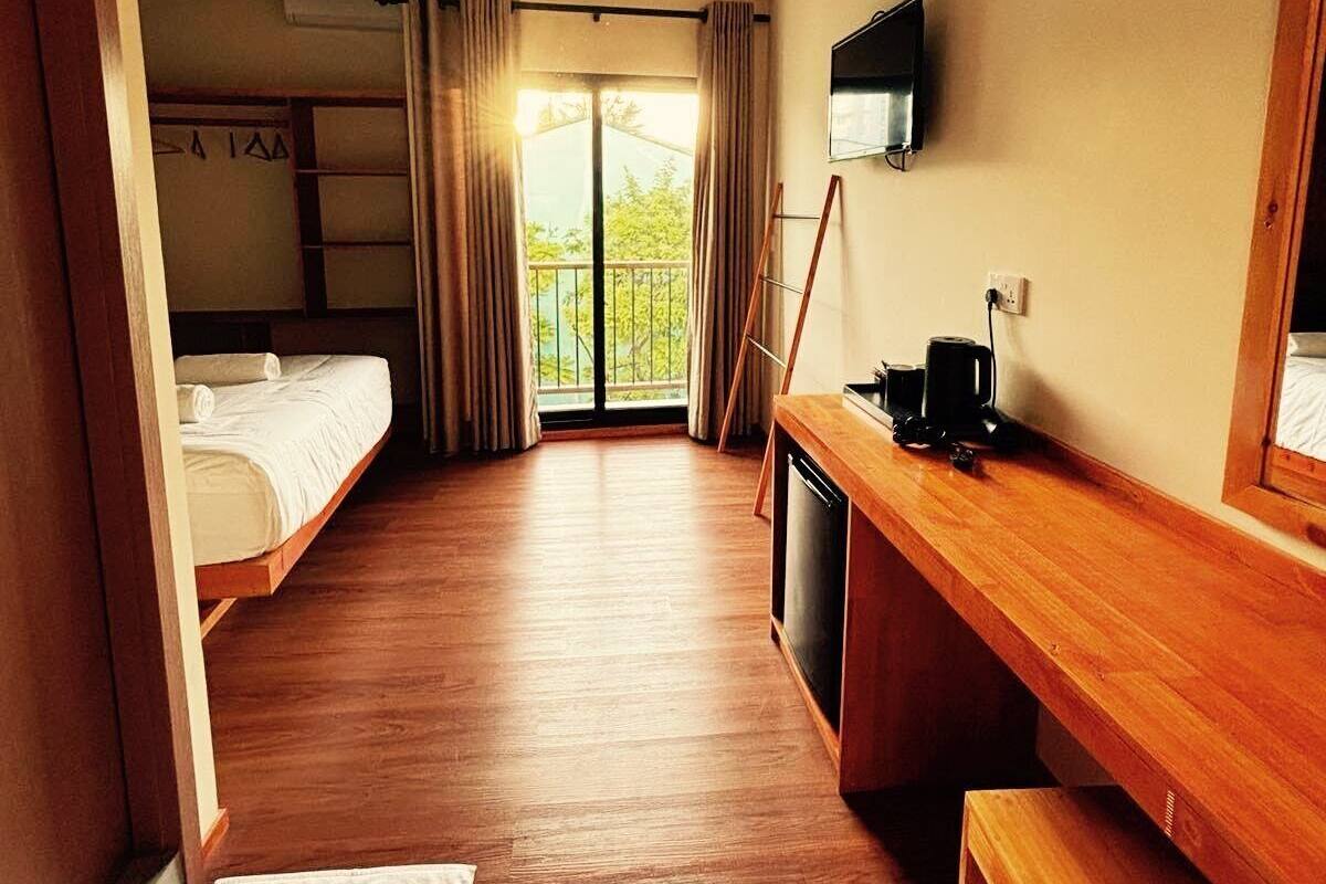 A hotel room with a bed, a desk, a coffee maker, a TV, and a balcony.