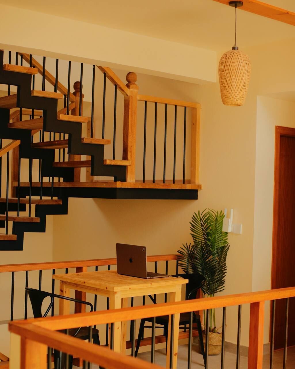 A wooden staircase with a laptop on a table below.