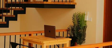 A wooden staircase with a laptop on a table below.
