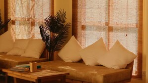 Una habitación con sofá, una mesa de centro, ventanas arqueadas amplias y una planta colgante.