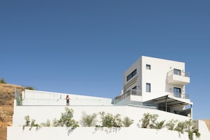 A modern building with a flat roof, multiple balconies, and a clear sky. - EmJo Villa, Heated Pool & Steps to the Beach (Panormos in Rethymno)