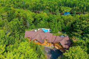 A log cabin with a swimming pool surrounded by dense forest.