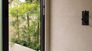 A modern bathroom with a large window, a showerhead, and a towel rack. - Private wellness home with pool, sauna, & cold plunge - in the center of Venice. (Los Angeles)
