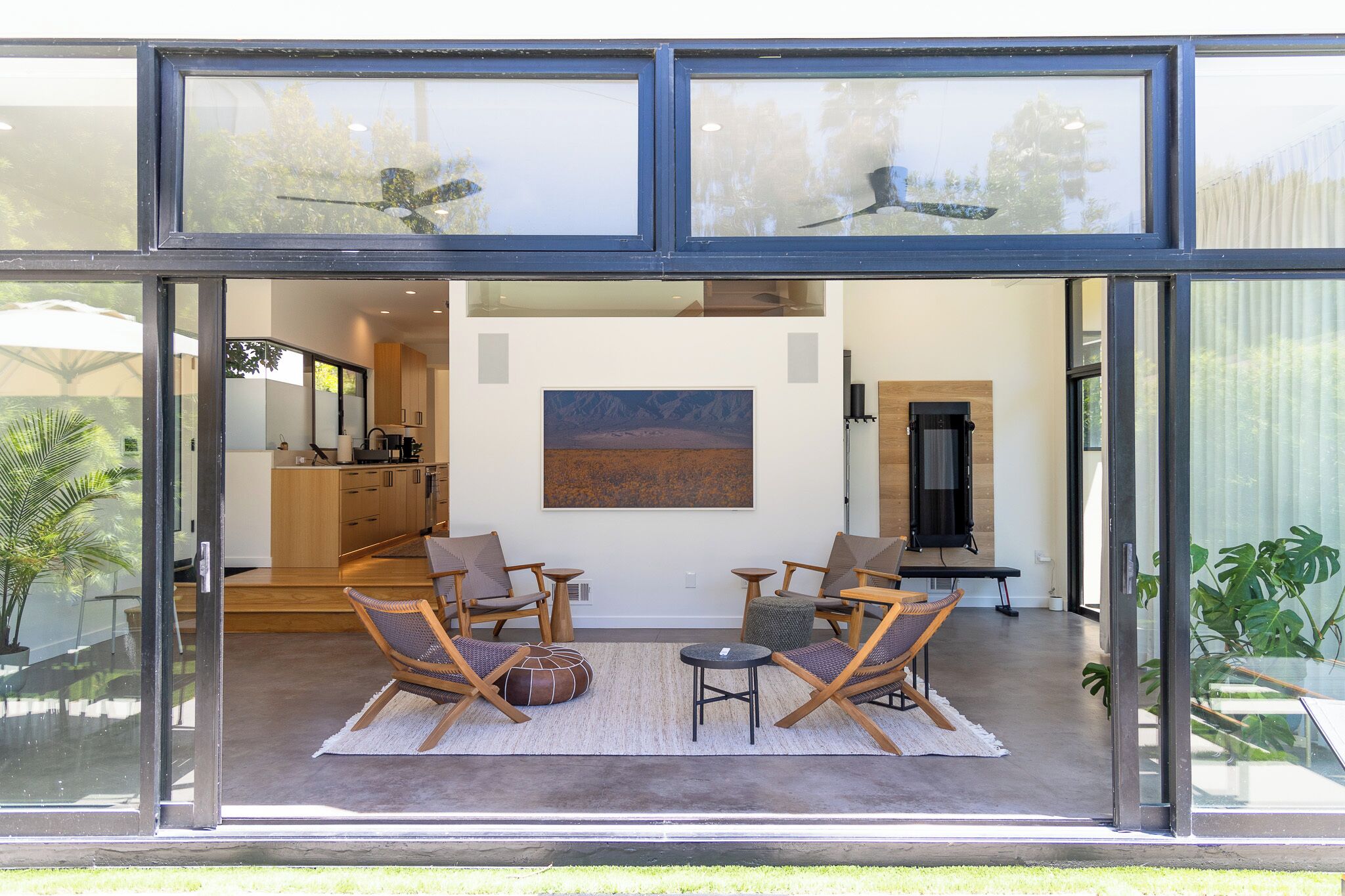 A modern interior with a glass wall, wooden furniture, and a painting on the wall.