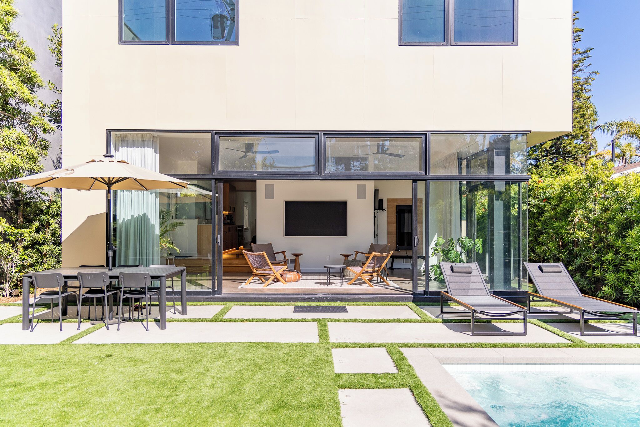 Een modern huis met een glazen gevel, een terras en een zwembad.