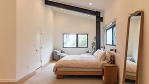 A modern bedroom with a large bed, a bedside table, a mirror, and a window. - Private wellness home with pool, sauna, & cold plunge - in the center of Venice. (Los Angeles)