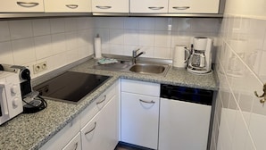 A kitchen with white cabinets, a stainless steel sink, a coffee maker, and a dishwasher. - Seaside - Central 2-room app. for 2-4 pers. with balcony and WLAN (Sylt)