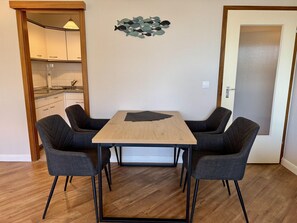 A dining area with a wooden table and four dark chairs. - Seaside - Central 2-room app. for 2-4 pers. with balcony and WLAN (Sylt)