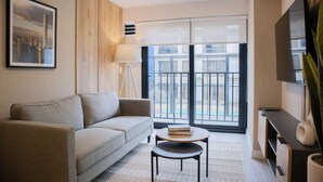 A modern living room with a sofa, a small table, a lamp, and a TV on a stand. - w* | Impressive 1BR w/ Balcony in Miraflores (Miraflores)
