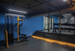Un gimnasio con equipamiento de levantamiento de pesas, un espejo y una escalera.