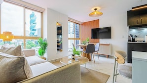 Un salon moderne comprenant un canapé, une table à manger, des chaises et un téléviseur.