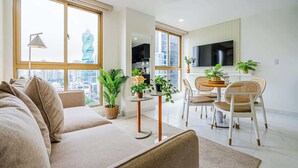 A modern living room with a sofa, dining table, chairs, and potted plants. - w* | Modern 1BR in the Heart of Obarrio (Panamá)