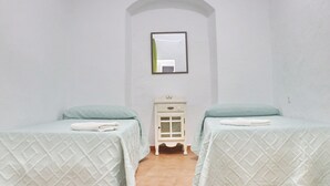A small, clean room with two beds, a small cabinet, and a mirror on the wall. - El patio de Tarifa . (Tarifa)