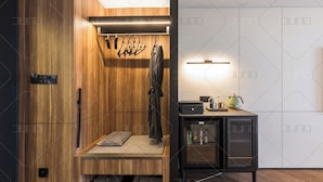 Een moderne, compacte kamer met een houten garderobe, een klein zithoekje en een kitchenette.