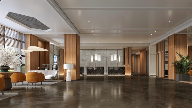 Een moderne lobby met een receptiebalie, een zithoek en grote ramen.