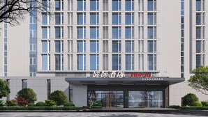 Een modern hotelgevel met een symmetrisch raamontwerp en een opvallende ingang.